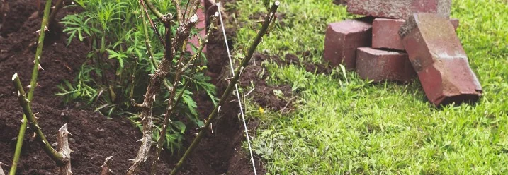 Ein Gartenbeet, davor liegen einige Steine und ein Spaten.
