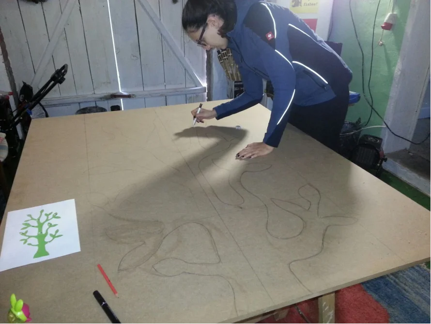Person zeichnet mit Stift auf Holzplatte