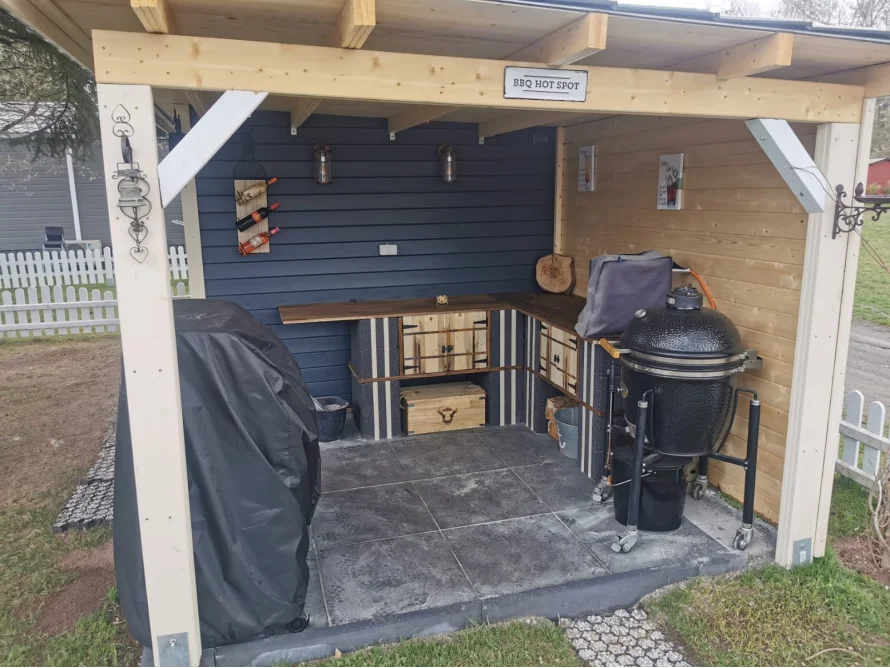 Außenküche mit Grillkamin unter einem Holzdach