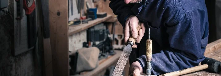 Person bearbeitet Holz mit Raspel