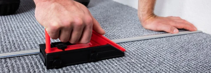 Person schneidet Teppich mit einem Cuttermesser