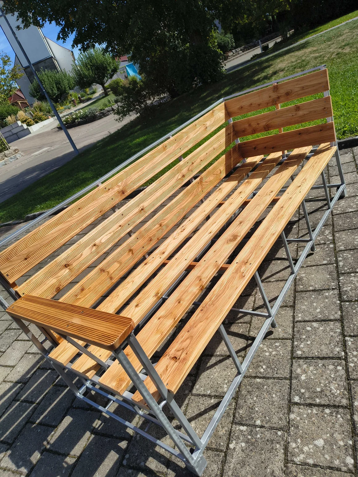 Eine lange Bank aus Holzlatten mit einem Metallgestell von oben fotografiert.