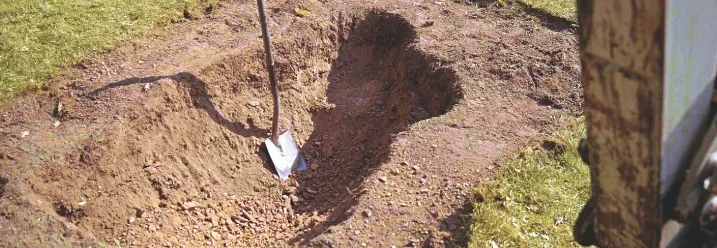 Ausgehobene Grube mit Spaten im Garten