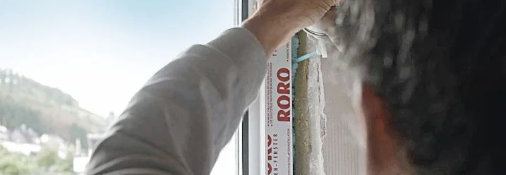 Person dichtet Fensterrahmen mit Schaum ab