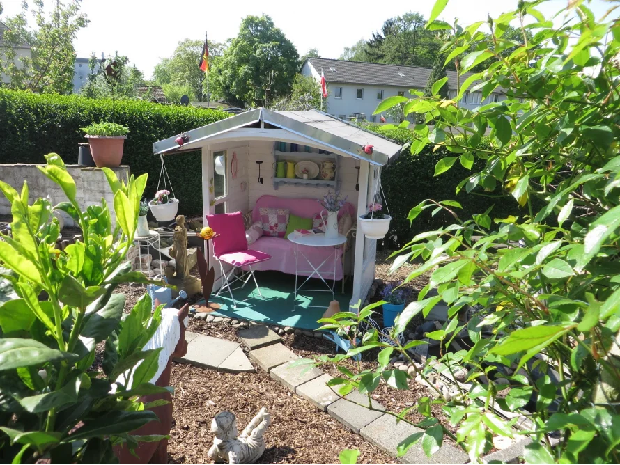 Kleines weißes Gartenhaus mit rosa Dekoration