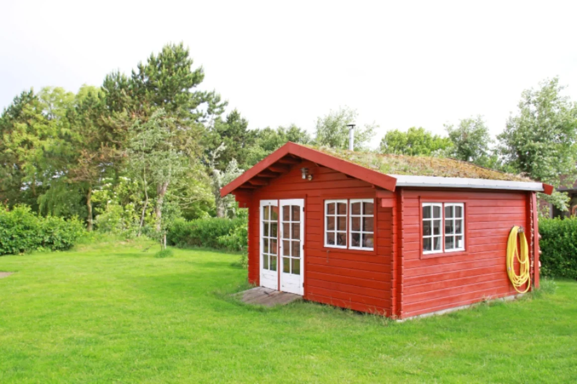 Rotes Gartenhaus mit begrünten Dach