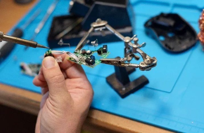 Person lötet Platine mit Lötkolben