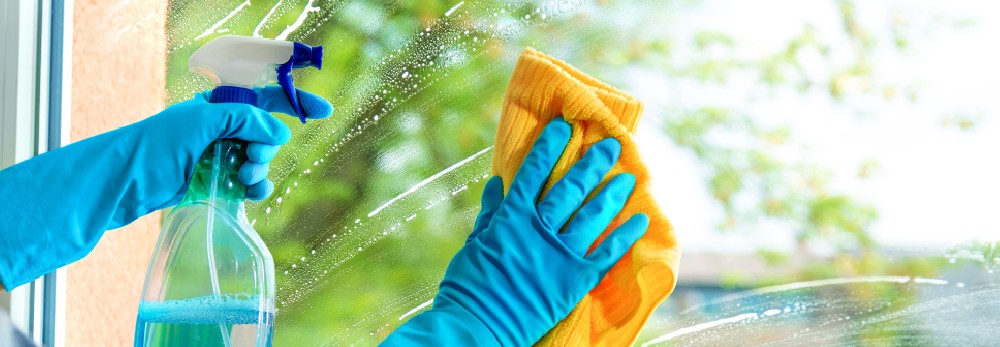 Hände mit Tuch und Sprühflasche reinigen Fenster