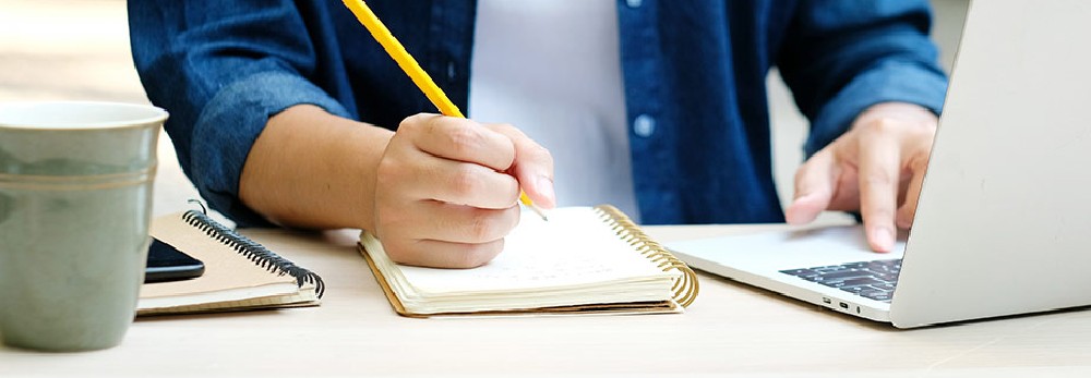 Person schreibt mit Stift in Notizbuch
