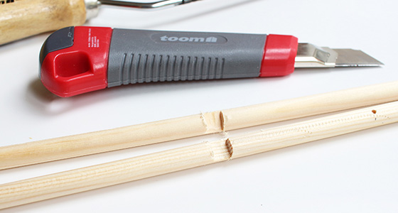 Zwei Holzstäbe und ein Teppichmesser